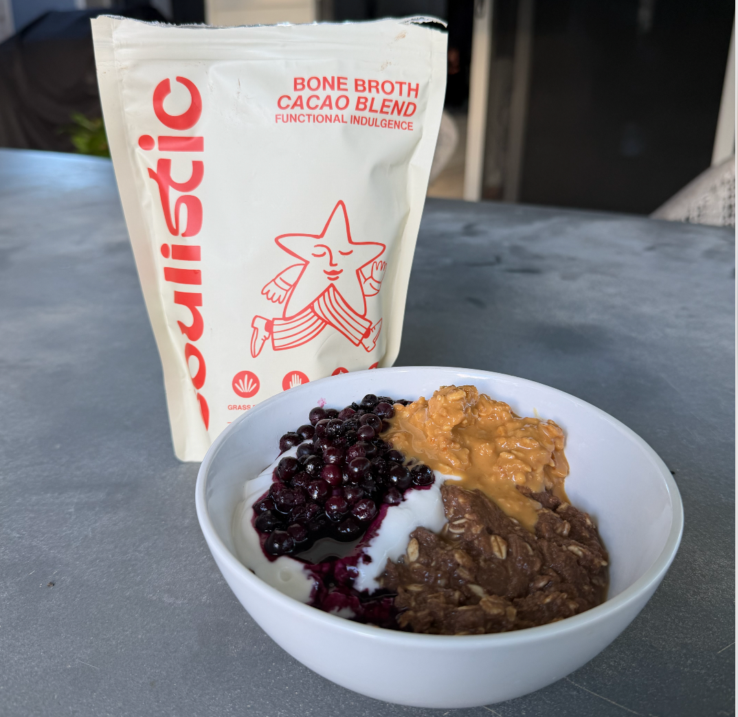 Bowl of creamy bone broth cacao oats topped with berries, yoghurt, and peanut butter
